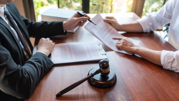 lawyer working with client discussing contract papers with brass