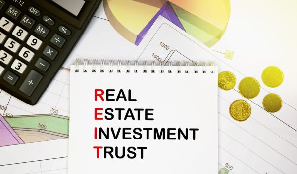 real estate investment trust on notepad with calculator, coins, graphics on financial report. business and financial concept