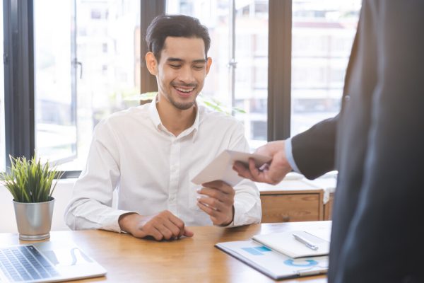 good job asian manager business man giving financial reward in an envelope, business letter extra salary to company employee, male worker office hand received premium bonus, getting cheque from boss.