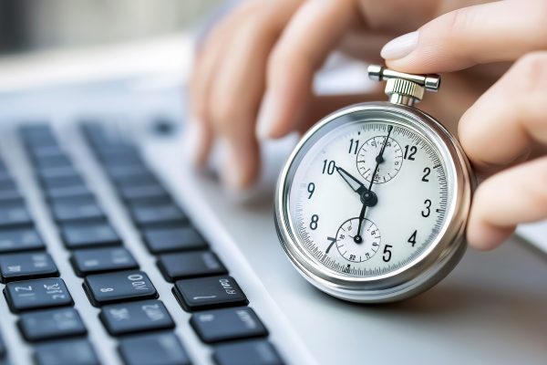 professional woman using a stopwatch while working on a laptop, concept of time tracking and efficiency.