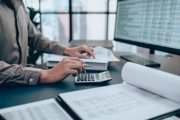 investors working on desk office and using a calculator to calcu