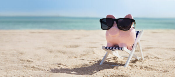 pink piggybank on deck chair over the sandy beach