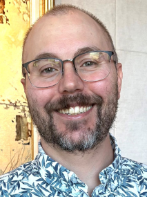 Headshot of Christopher Bezerra-Clark, Client Accounting Services Associate at R&A, smiling and wearing glasses and a patterned shirt.