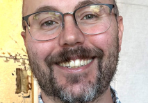 Headshot of Christopher Bezerra-Clark, Client Accounting Services Associate at R&A, smiling and wearing glasses and a patterned shirt.
