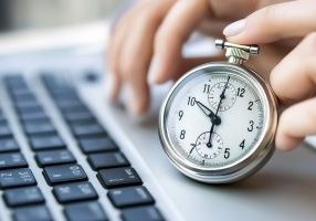 professional woman using a stopwatch while working on a laptop, concept of time tracking and efficiency.