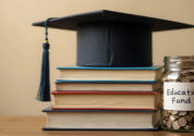 Pile of books with a graduation Hat on top with a jar full of coins