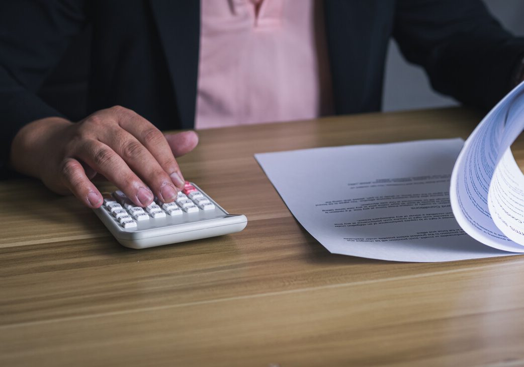 businessman using calculator and reviewing financial documents at desk. concept of accounting, finance, auditing, tax, and business analysis.
