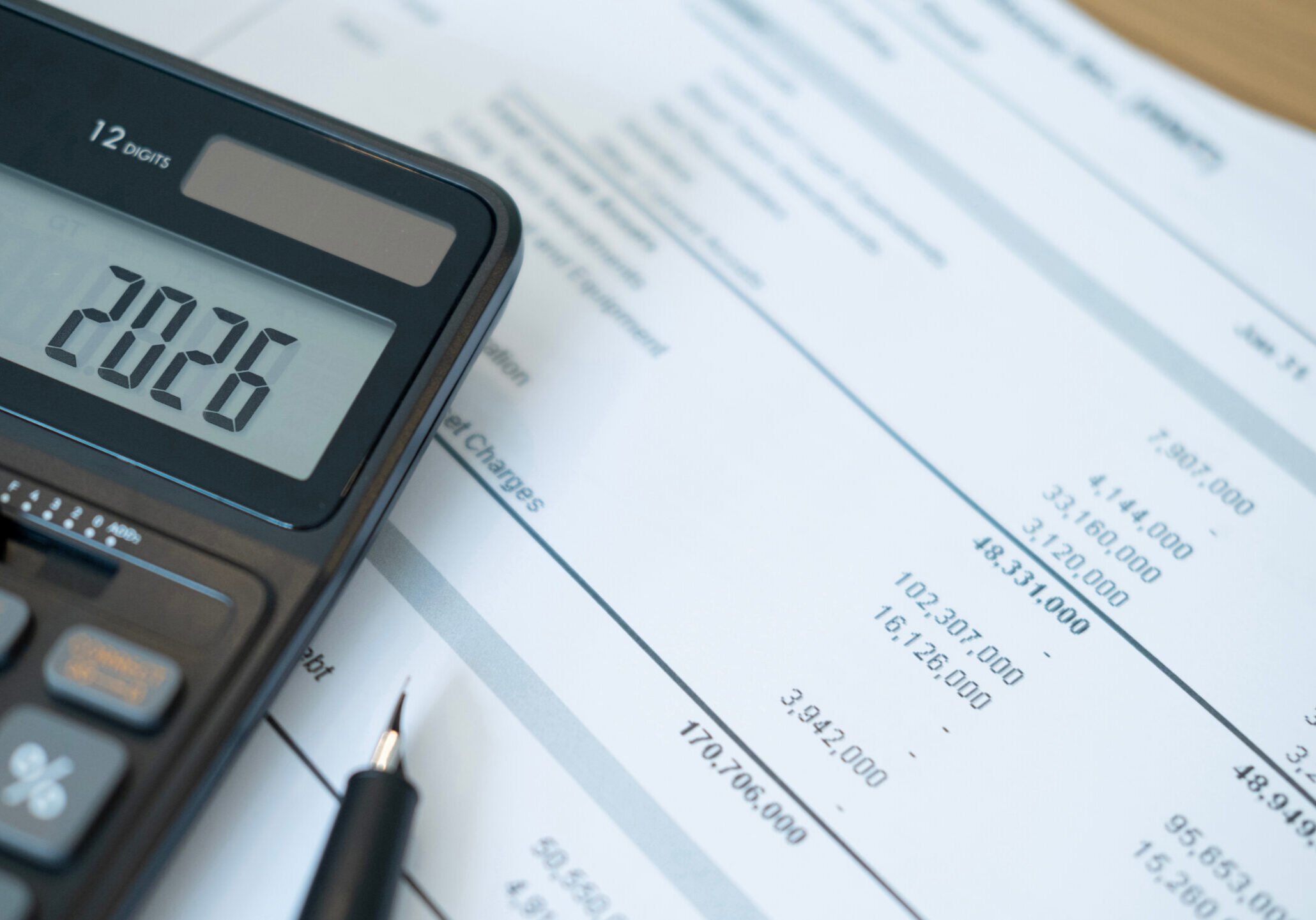 close up of black calculator screen showing 2026 with detailed financial reports underneath. this composition highlights data analysis and preparation for upcoming financial decisions.