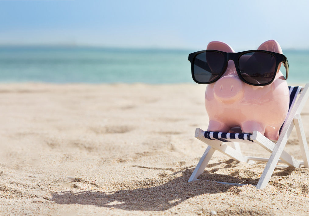 pink piggybank on deck chair over the sandy beach