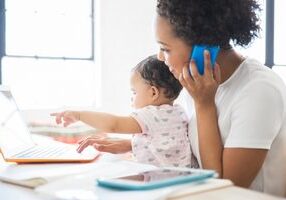 mother working from home with daughter sitting on her lap