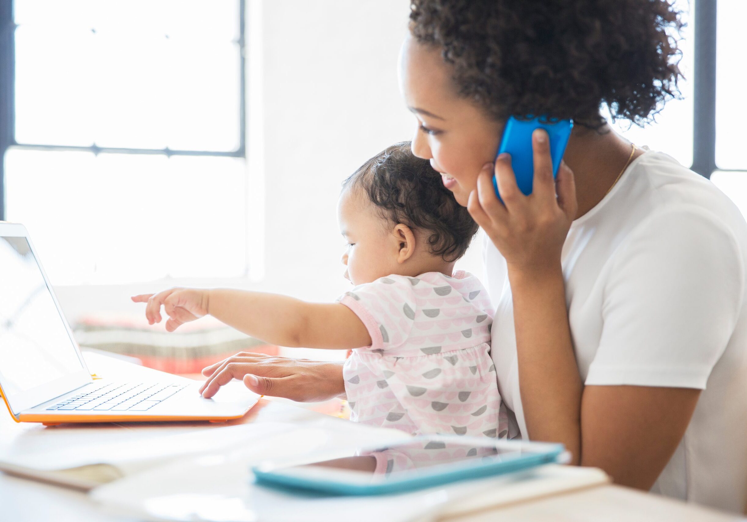 mother working from home with daughter sitting on her lap