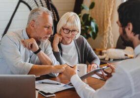 financial advisor explaining paperwork to elderly retired couple front of desk