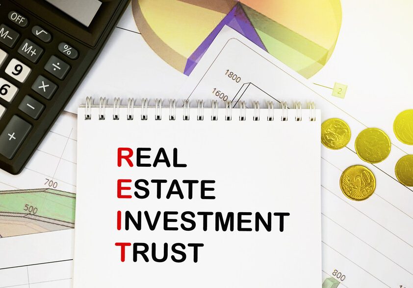 real estate investment trust on notepad with calculator, coins, graphics on financial report. business and financial concept