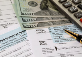 amount you owe line on income tax return forms, cash money and calculator. federal tax return, income tax, tax refund and payment concept.